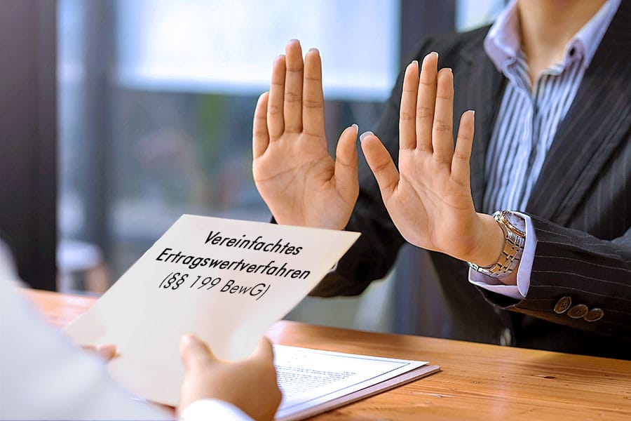 Das Bild zeigt die beiden Hände einer Geschäftsfrau in Abwehrhaltung gegenüber einem Kuvert mit Aufschrift „ vereinfachtes Ertragswertverfahren nach § 199 BewG “, das die Hände einer anderen Person ihr reichen möchte.
